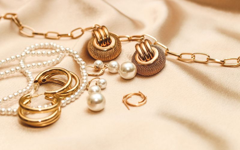 Plusieurs paire de boucles d'oreilles de style différents, présentées sur un tissu beige satiné