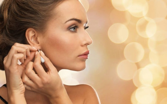 Femme de profil qui enfile une boucle d'oreille.