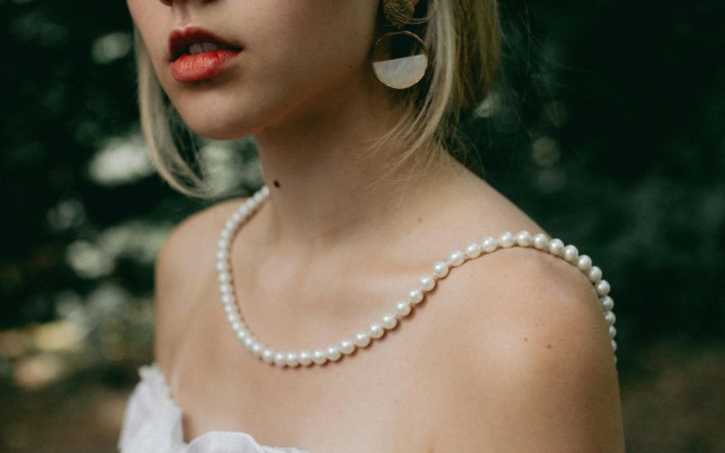 Femme qui porte une boucle d'oreille magnétique, la photo montre que le bas de son visage et le haut de son buste.