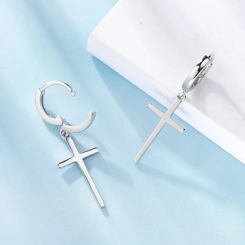 Boucle d'Oreille Croix Femme en Cuivre Couleur Argenté posé sur un socle et un tissu