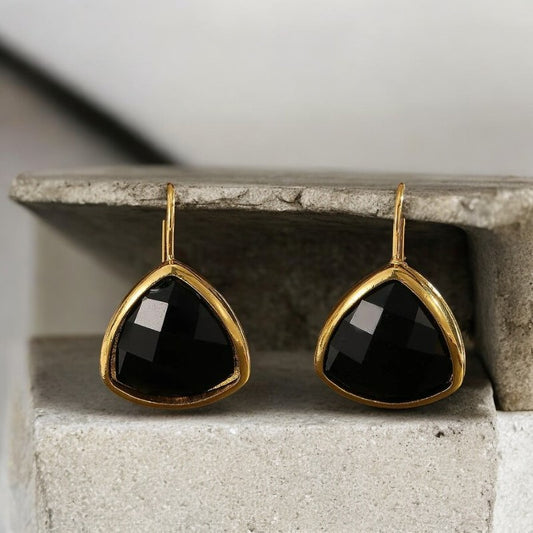 Boucle D'oreille Luxe Vintage effet diamant noir, présenté sur un socle en pierre.