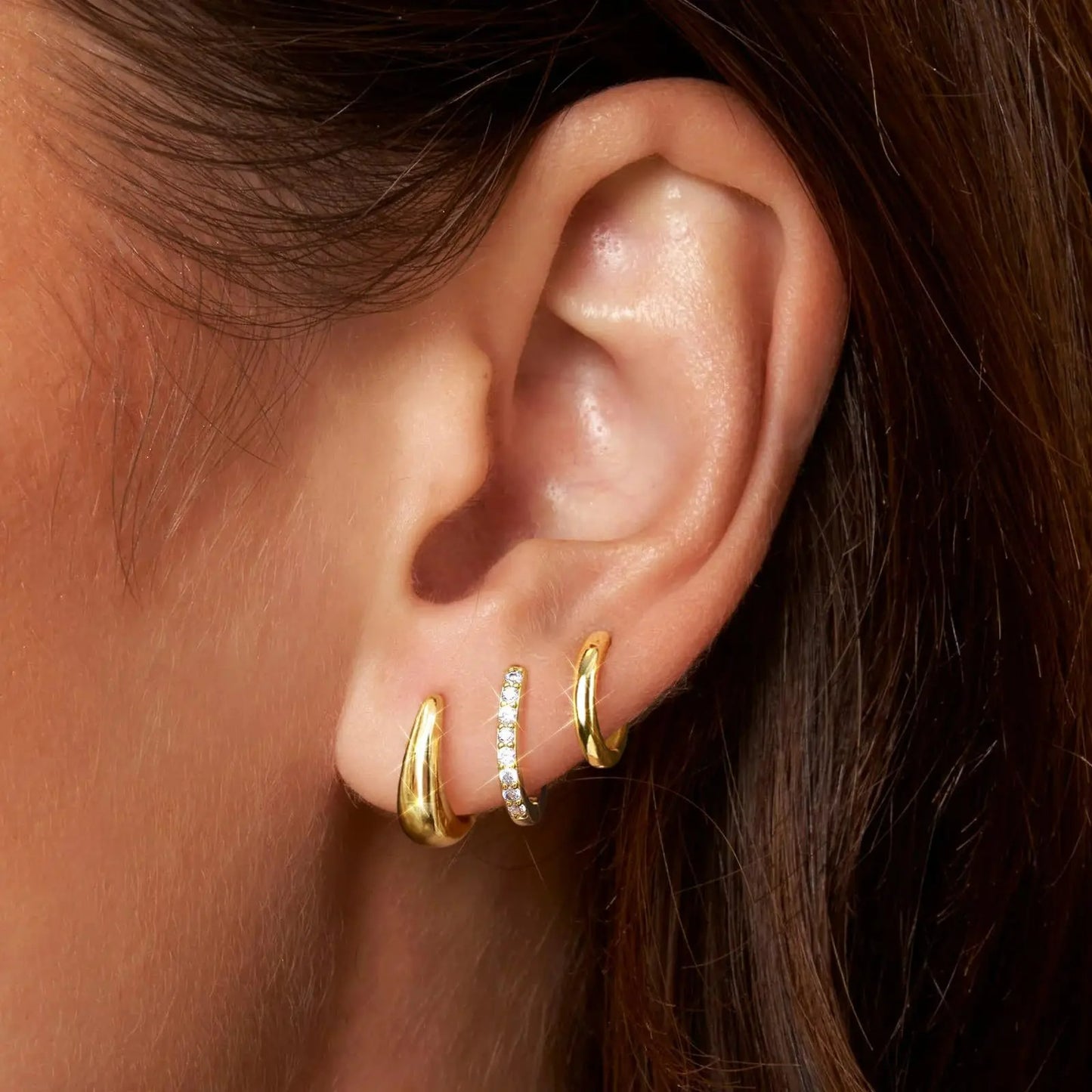 Lot 3 Paires Boucles D'oreilles Créoles Dorées, portées par une femme on ne voit que son oreille