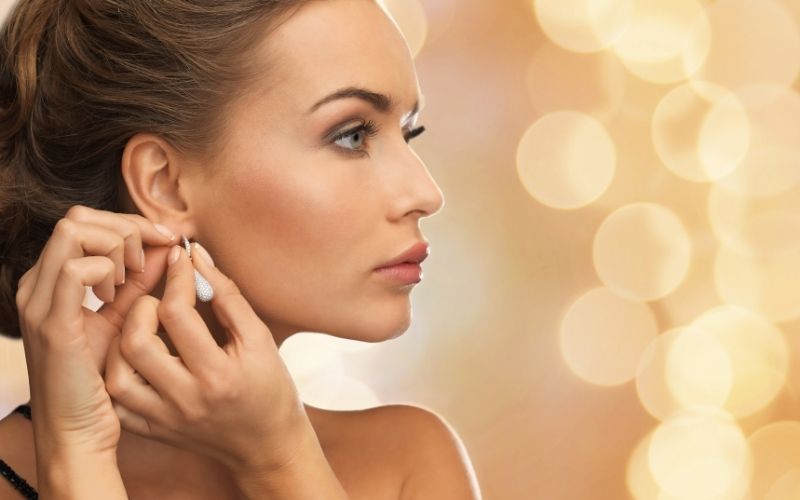 Femme de profil qui enfile une boucle d'oreille.
