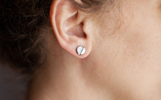 Photo d'une boucle d'oreille médicale sur l'oreille d'une femme de profil, on ne voit que son oreille.