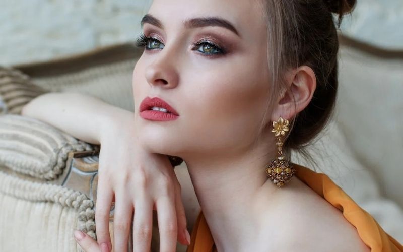 Femme bien maquillé et coiffer, qui pose pour un shooting, elle porte une longue boucle d'oreille a pince très chic. Image