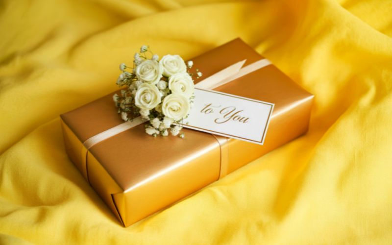 Coffret cadeau jaune brillant avec mini bouquet de roses sur un tissu jaune.
