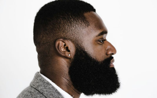 Homme de profil avec une belle barbe et des cheveux courts, une boucle d'oreille diamant synthétique.