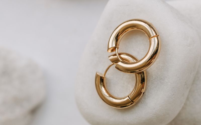 Paire de créoles dorées plutôt épaisses, présenté sur une pierre blanche