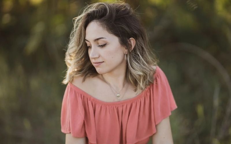 Femme, cheveux lâchés, tête de profil, portant une robe a volant qui tombe sous les épaule, et une paire de créole simple et chic