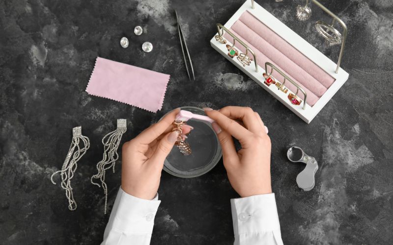 Personne qui nettoie des boucles d'oreilles avec une solution et une brosse à dent, vu d'en haut.
