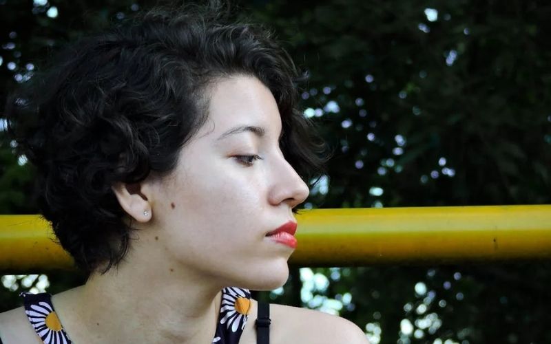 Femme de profil, portant une boucle d'oreille puce et les cheveux courts.