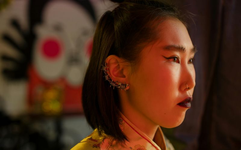 Femme cheveux noir au carré de profil, portant un ear cuff qui monte sur toute l'oreille effet barbelé. le fond est flou Image
