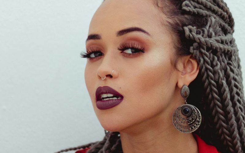 Femme qui regarde l'objectif, qui porte une boucle d'oreille pendante originale.