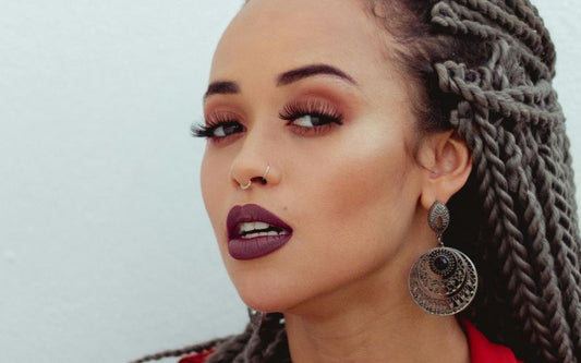 Femme qui regarde l'objectif, qui porte une boucle d'oreille pendante originale.