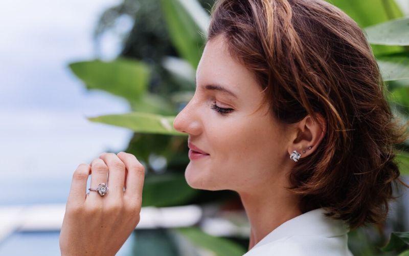 Femme de profil avec un carré court, portant trois boucles d'oreilles sur la même oreille.