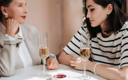 Deux femmes assise à une table qui boivent une coupe de champagne.