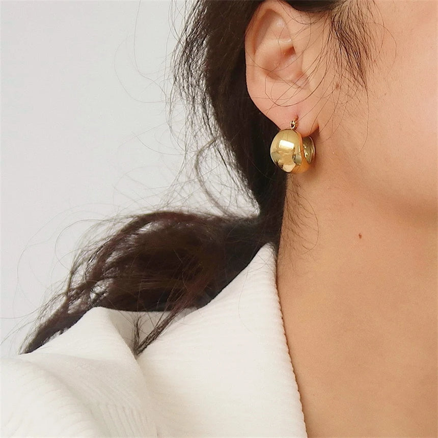 Boucle D'oreille Acier Inoxydable Épaisse style Rétro, portée par une femme, on voit son coup et son oreille, elle se tient de 3/4.