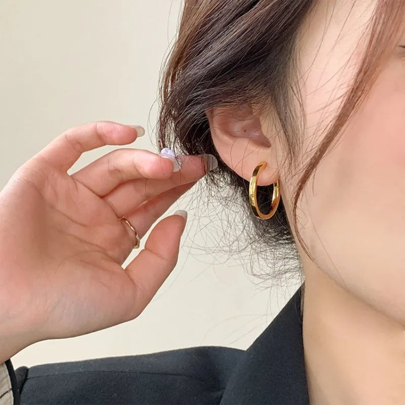 Boucle D'oreille Anneau Femme Simple Dorée, portée par une femme, on ne voit que son oreille Image