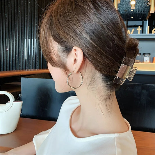 Boucle D'oreille Anneau Femme Texturé Et Torsadé, portée par une femme de trois quart dos.