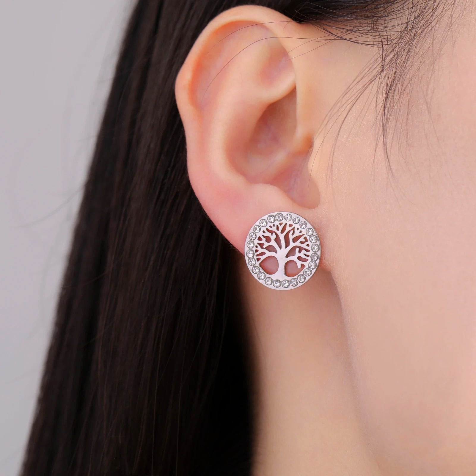 Boucle D'oreille Arbre De Vie Acier Inoxydable argenté portée par une femme de profil, on ne voit que son oreille et sa nuque.
