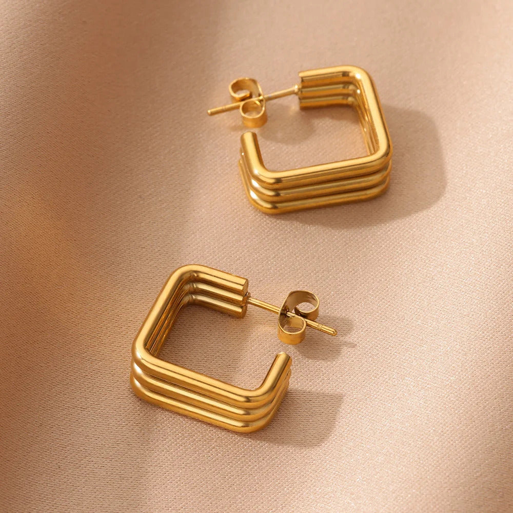 Boucle D'oreille Carré Design en Acier inoxydable posé sur un fond beige  Image