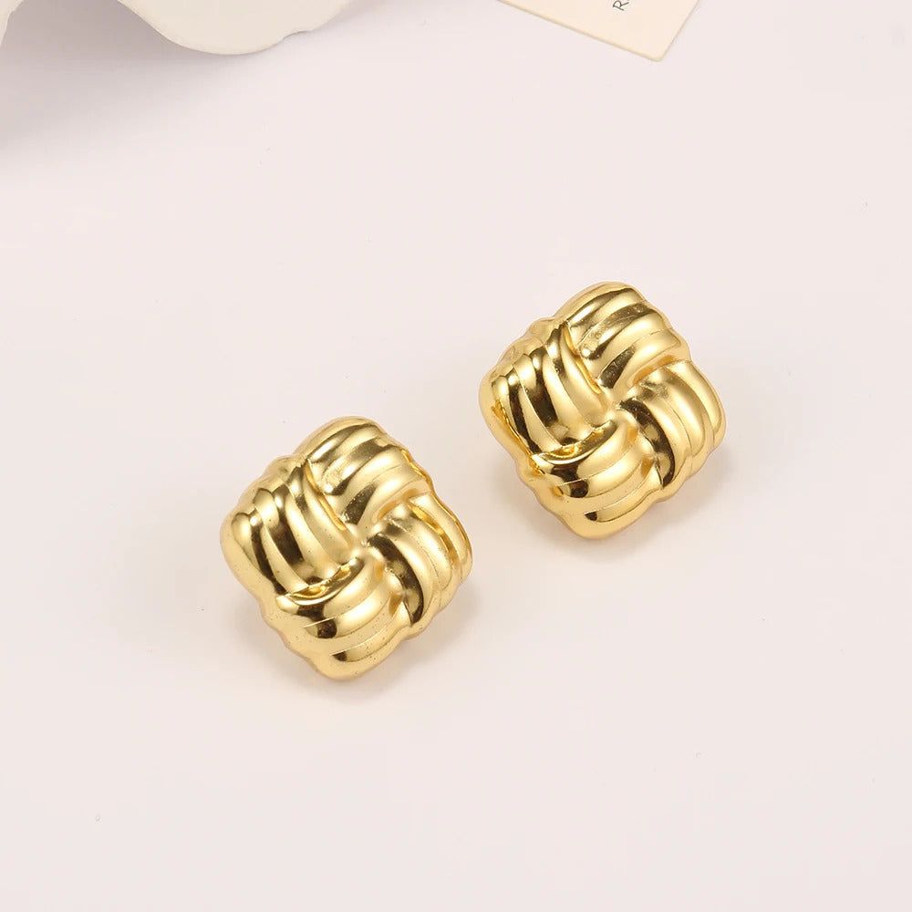 Boucle D'oreille Carré Design Minimaliste et Doré posé sur un fond beige 