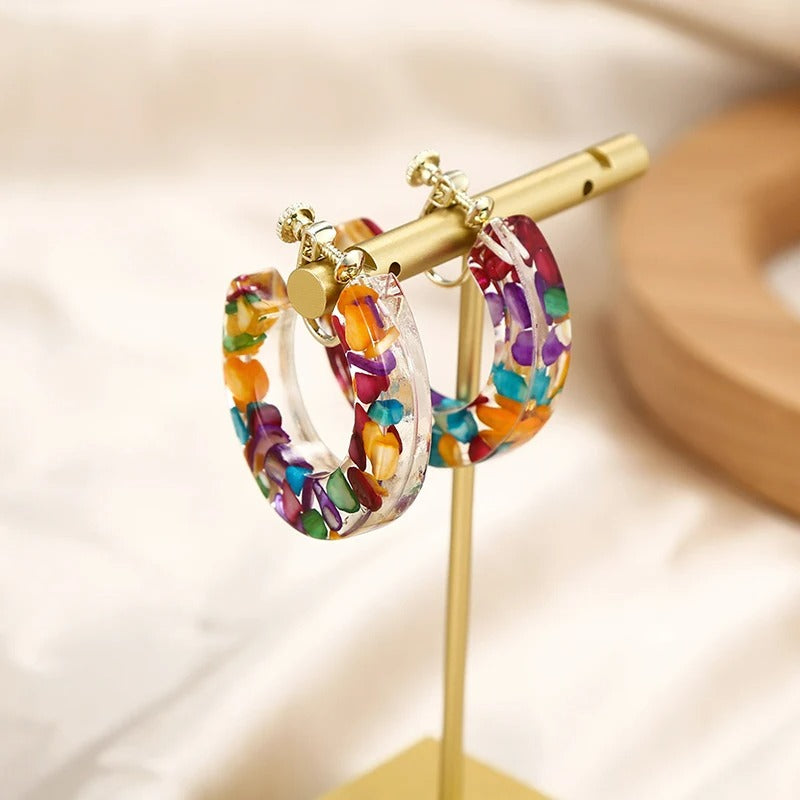 Boucle D'oreille Clip Femme Créole Colorée posée sur un présentoir en métal doré Image