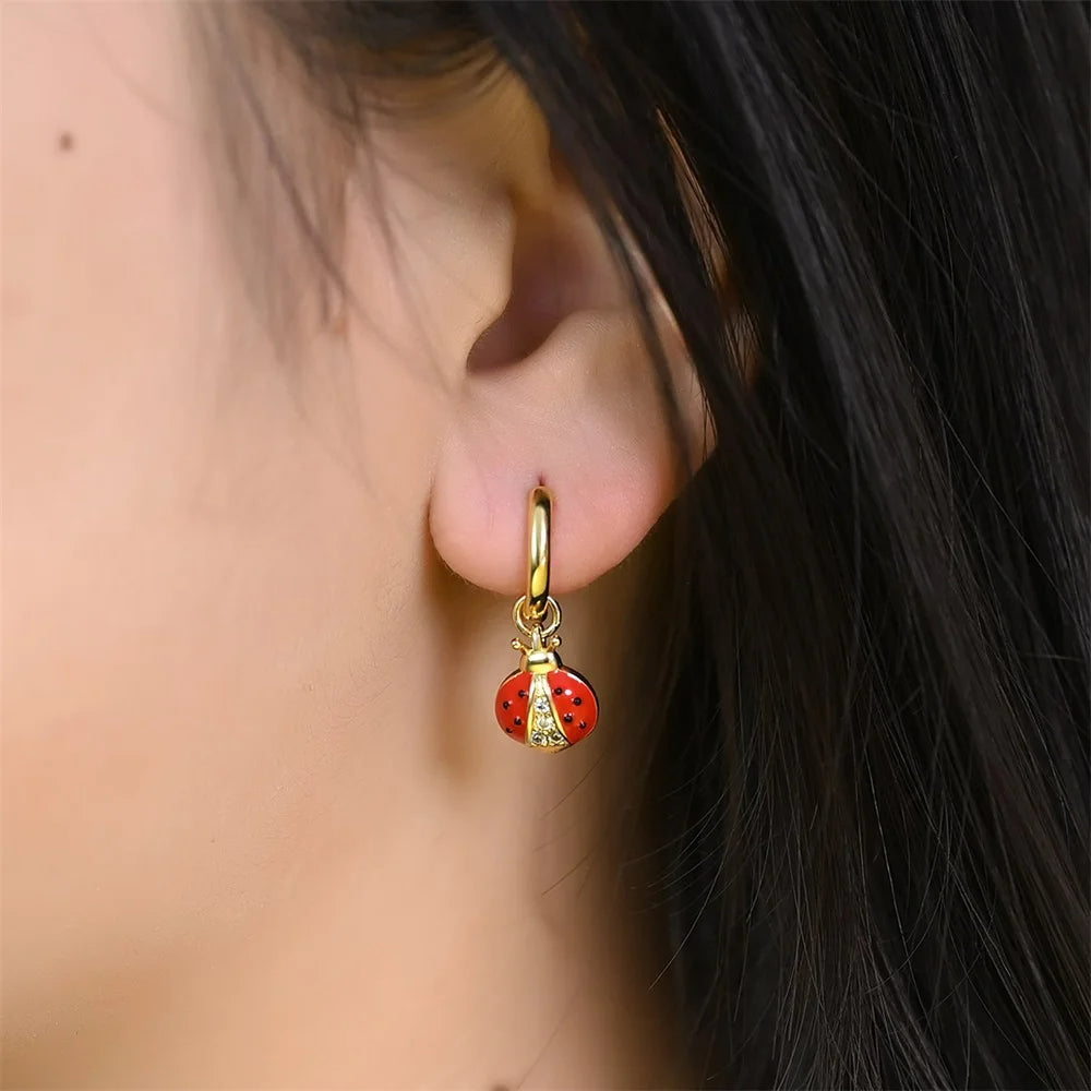 Boucle D'oreille Coccinelle Pendante, porté par une femme, on ne voit que son oreille et ses cheveux. Image