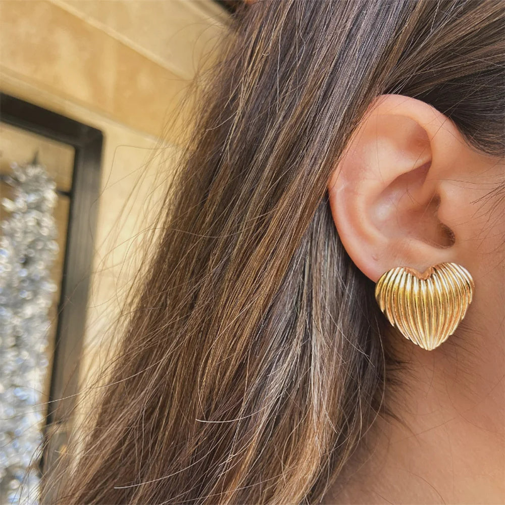 Boucle D'oreille Cœur Effet Coquillage, portée par une femme aux cheveux détachés, elle est de profil.