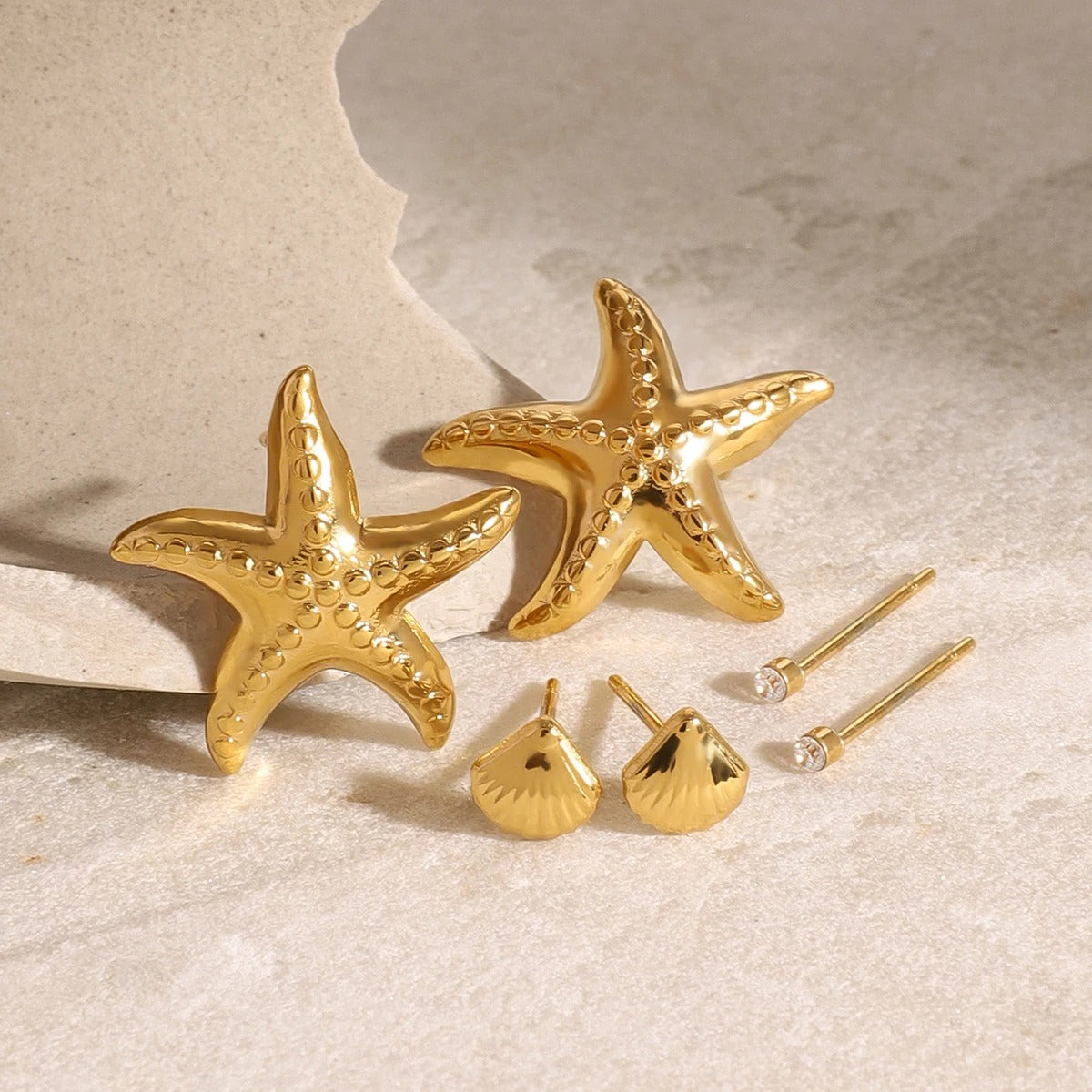 Boucle D'oreille Coquillage Acier Inoxydable Lot De 3 présentées sur de la pierre beige