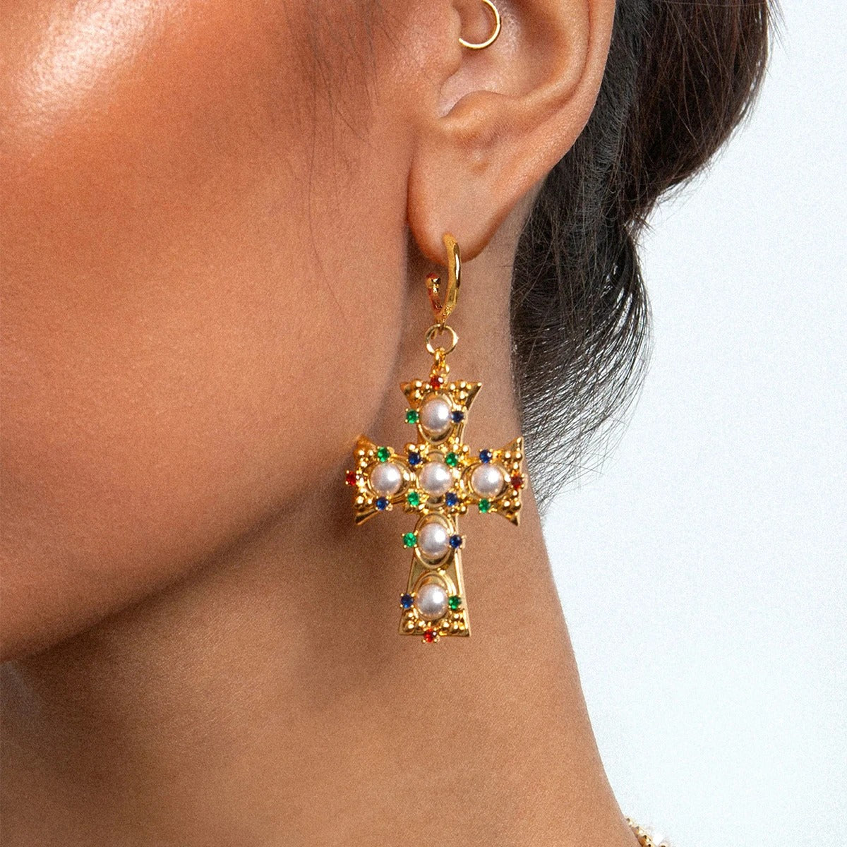 Boucle D'oreille Croix Femme Byzantine en Acier Inoxydable, portée par une femme de profil on ne voit que son oreille.