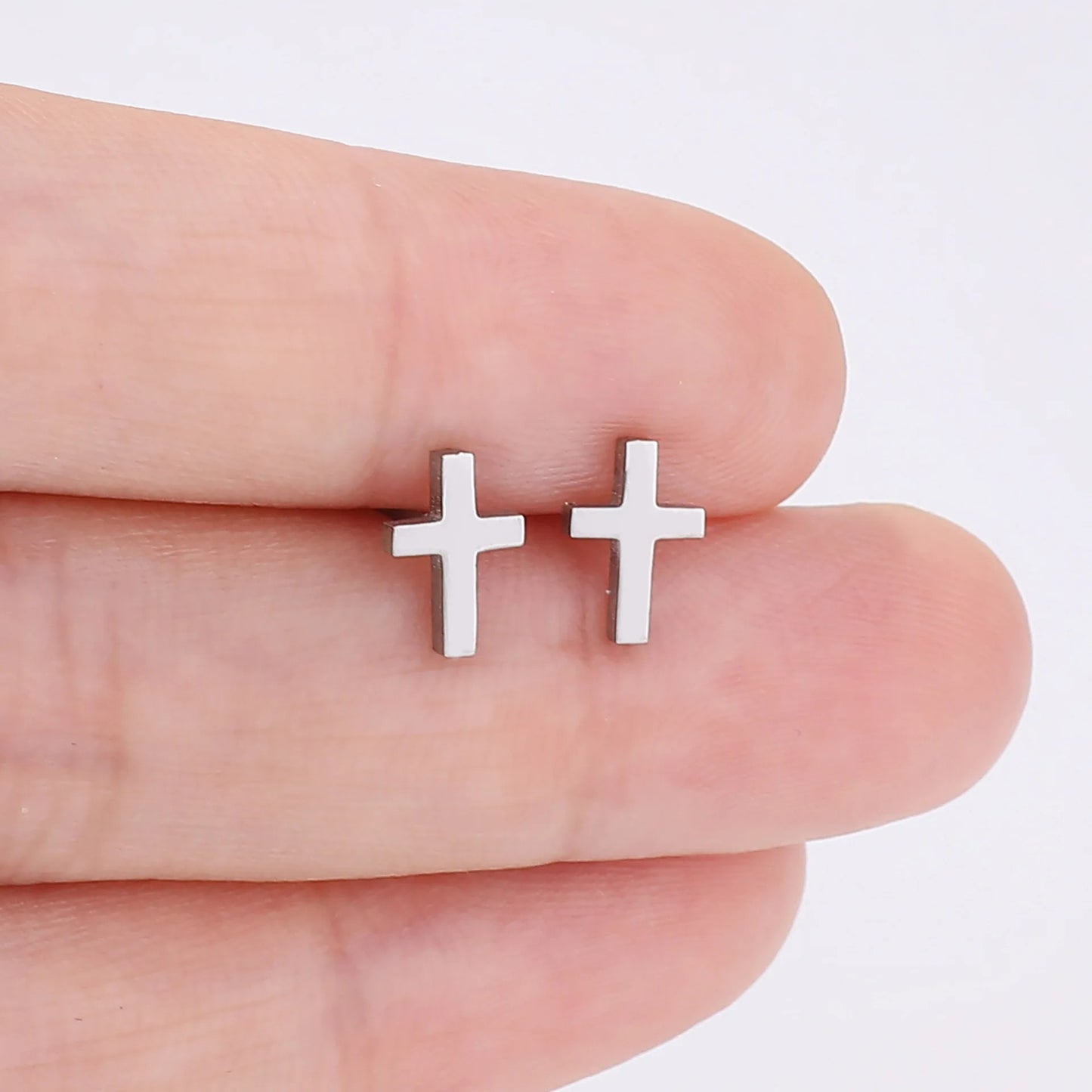 Boucle D'oreille Croix Homme Minimaliste Acier Inoxydable présenté eentre les doigts d'une personne