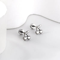 Boucle d'Oreille Enfant Acier Inoxydable Cerises, présenté sur un plan de travail gris très clair.