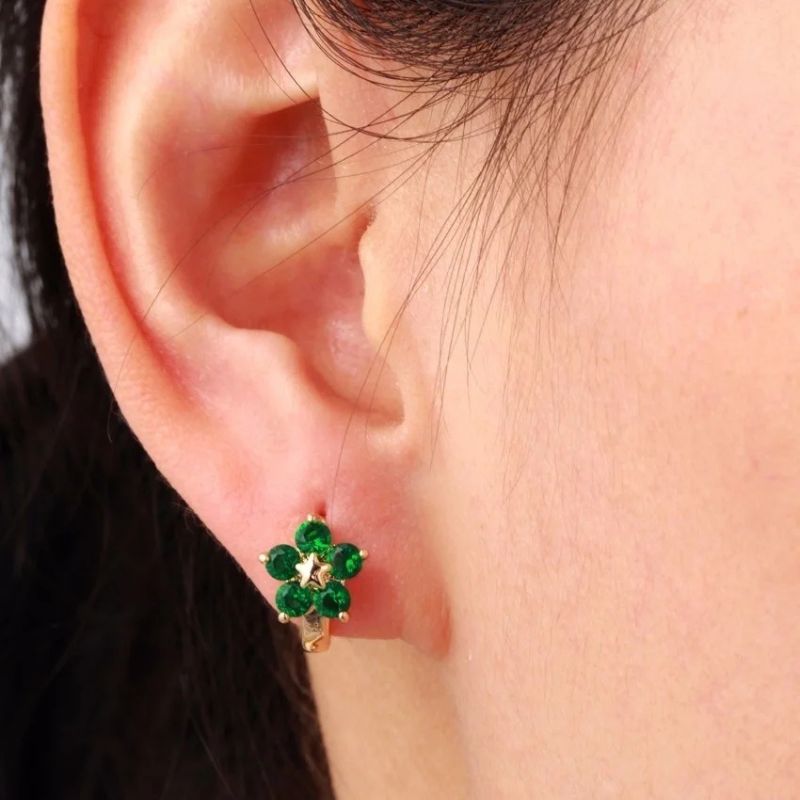 Boucle d'Oreille Enfant Créole Fleur Verte, portée par une jeune fille, on ne voit que son oreille. Image