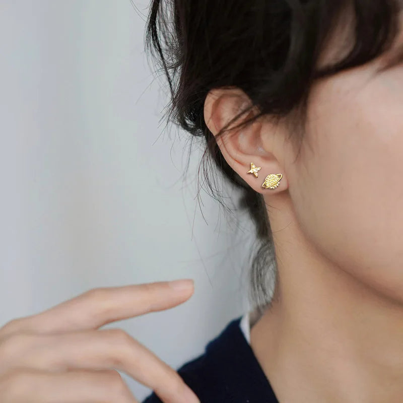 Boucle d'Oreille Enfant Dépareillée Galaxie, portée par une mannequin, on ne voit que son oreille et son cou. Image