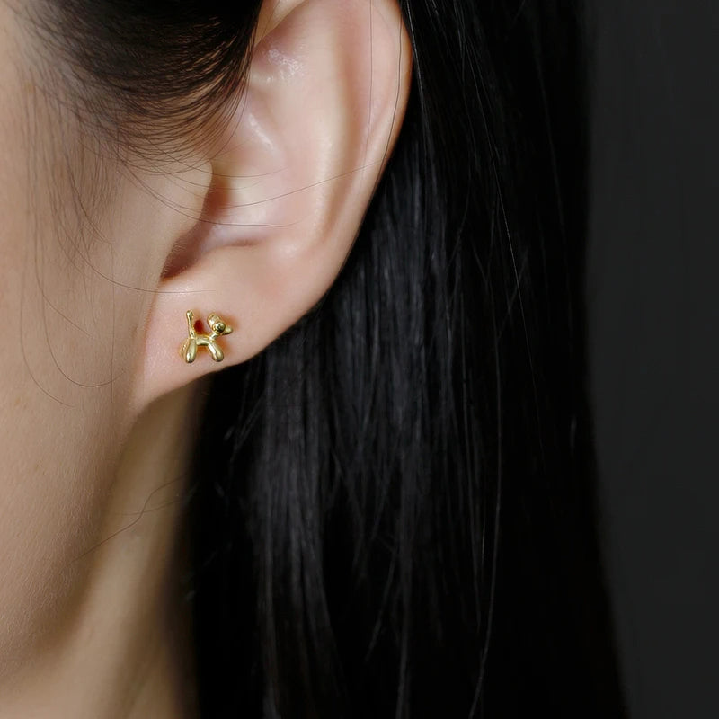 Boucle d'Oreille Enfant Dorée Petit Chien, porté par une jeune fille, les cheveux détachés, on ne voit que son oreille et ses cheveux. Image
