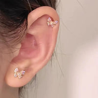 Boucle d'Oreille Enfant Papillon Acier Inoxydable, portée par une mannequin, une boucle sur le lobe et une autre sur le cartilage haut de l'oreille.
