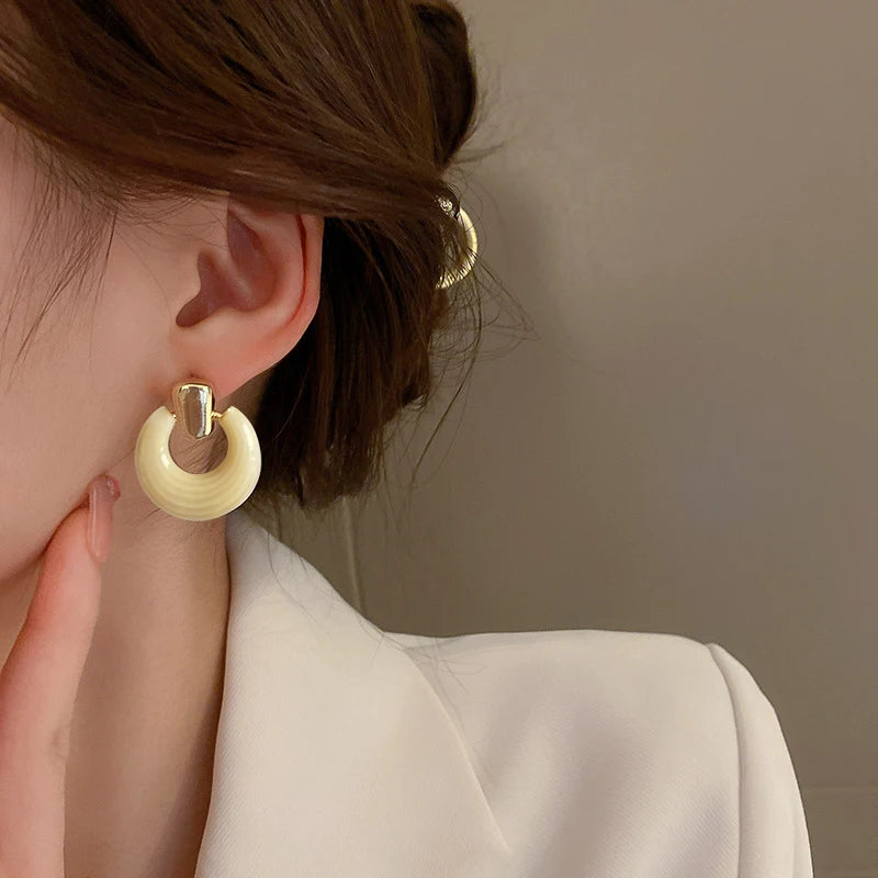 Boucle D'oreille Femme blanche vintage, portée par une femme avec une veste de tailleur blanche.