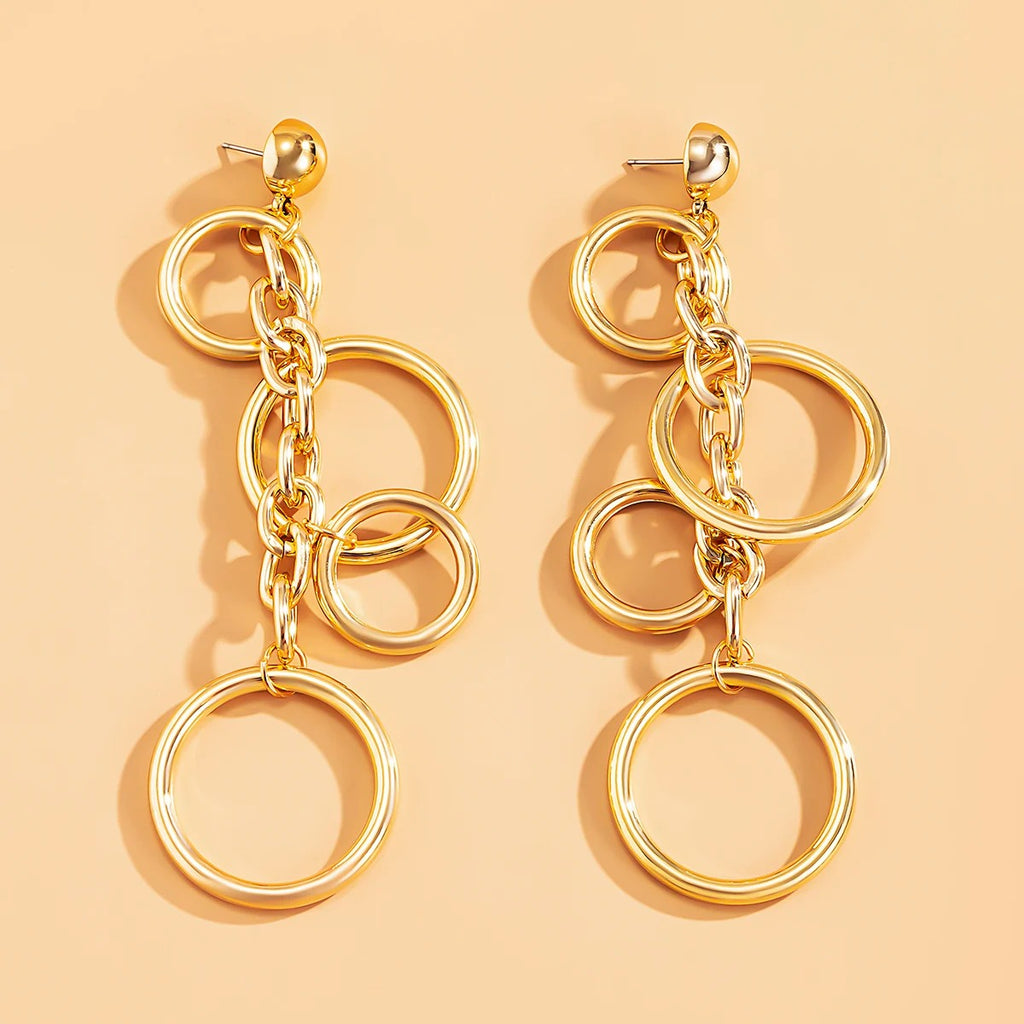 Boucle d'Oreille Femme Pendante Carré Design Moderne posé sur un fond orange 