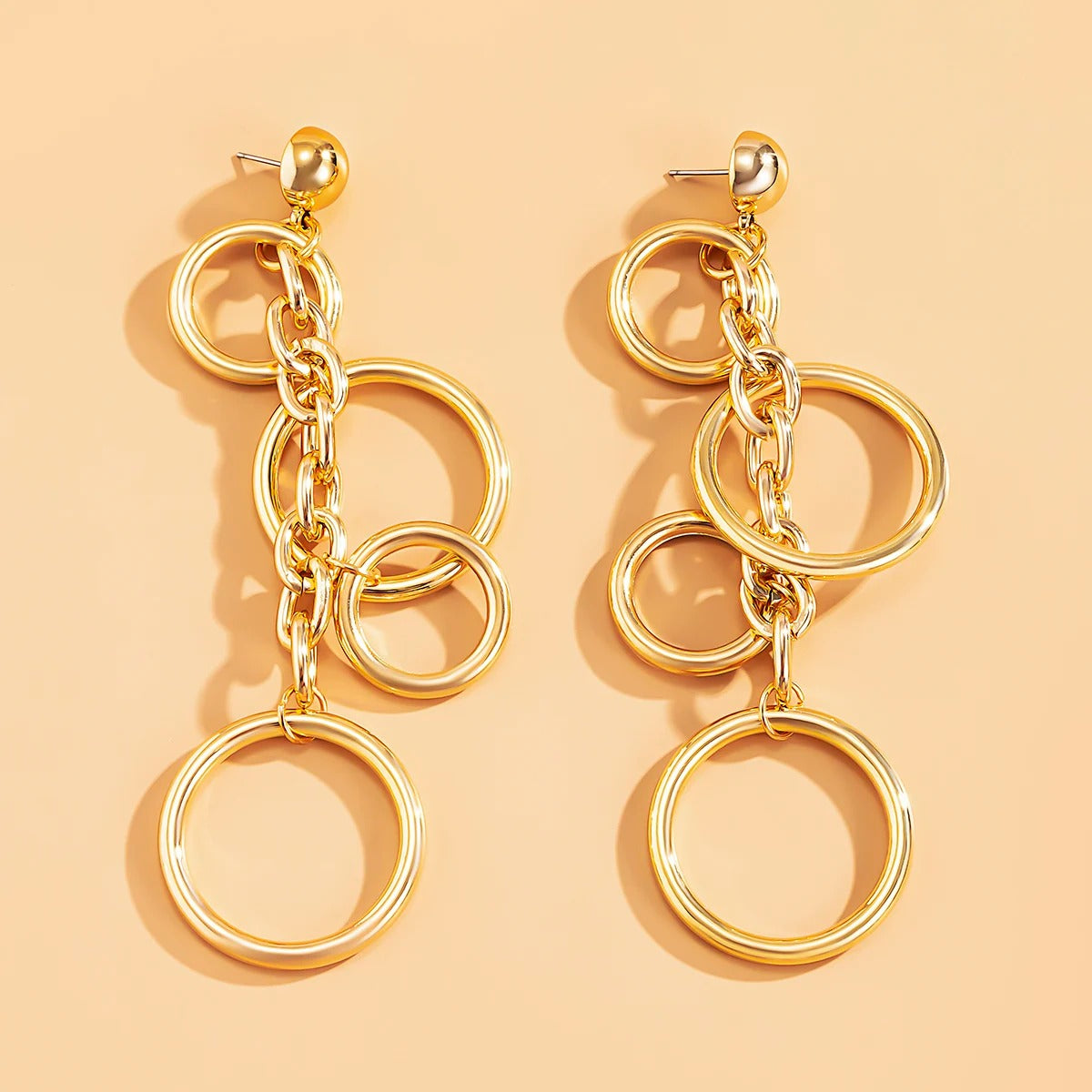 Boucle d'Oreille Femme Pendante Carré Design Moderne posé sur un fond orange 