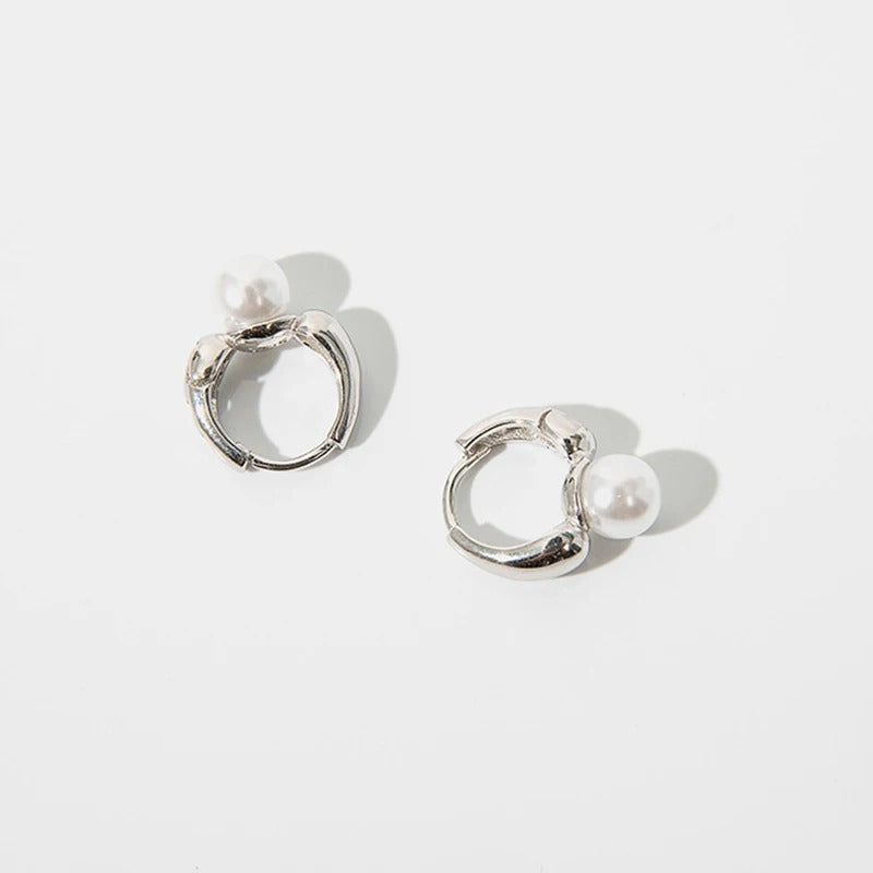 Boucle d'Oreille Femme Perle Design Croisé posé sur un fond blanc 