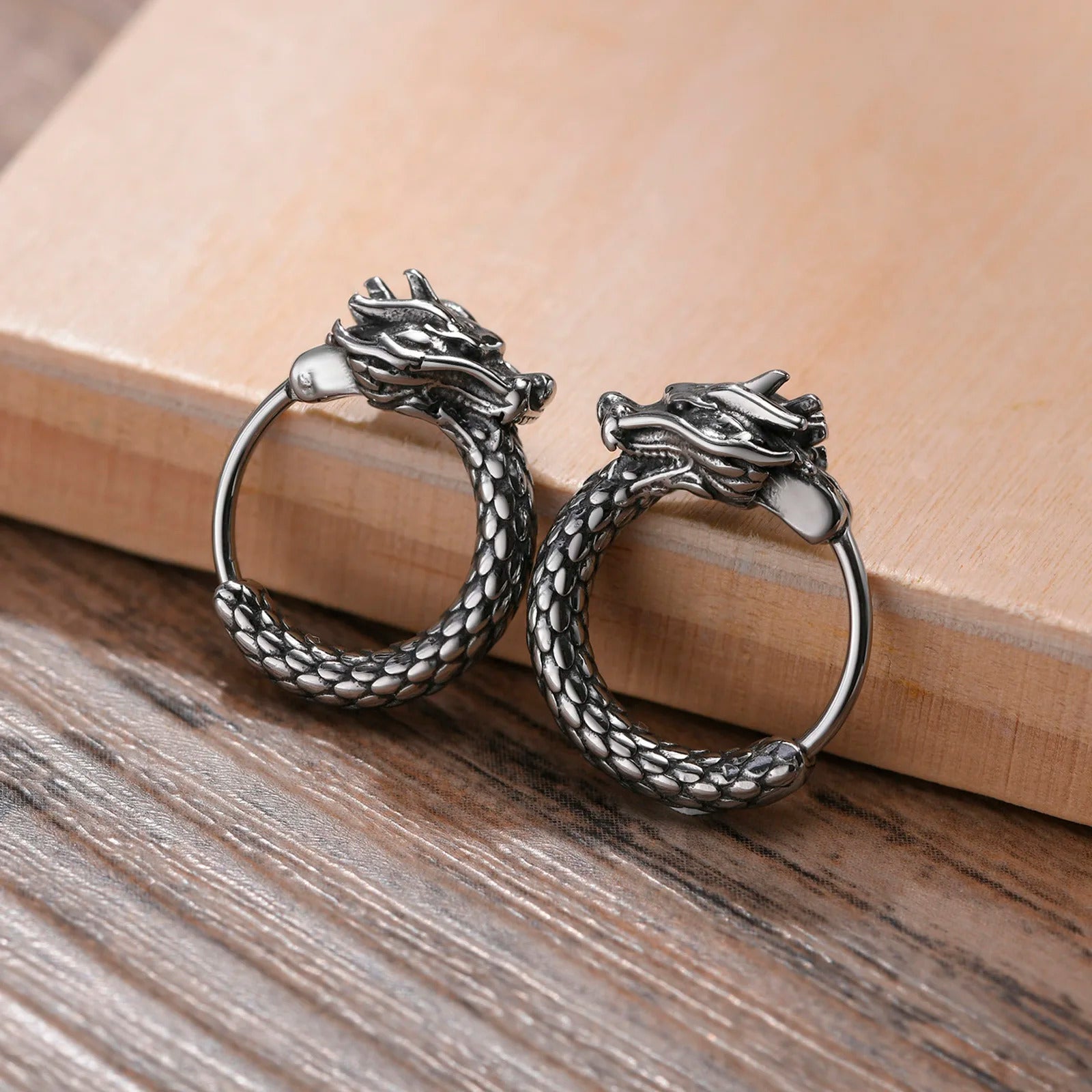 Boucle D'oreille Homme Anneau avec Design de Dragon posé sur une table en bois 