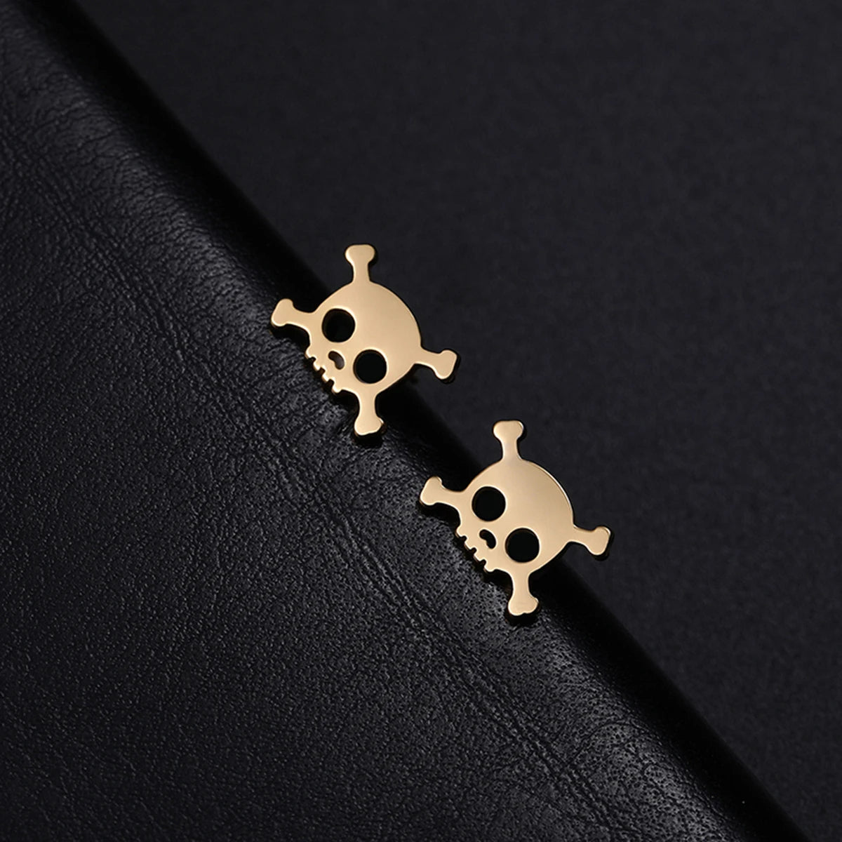 Boucle D'oreille Homme Discret Crâne en Acier Inoxydable présenté sur une planche recouverte de cuir noir.