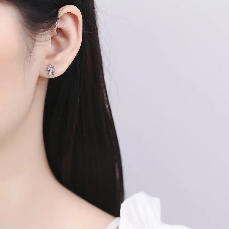 Boucle D'oreille Licorne Paillettes, argenté, portée par une jeune fille aux cheveux noirs, on ne voit que son oreille. Image