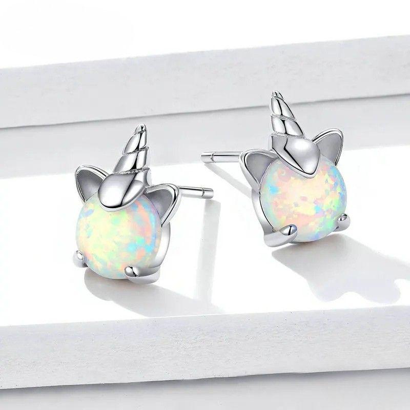 Boucle D'oreille Licorne Pierre Effet Opale sur un présentoire blanc en paire
