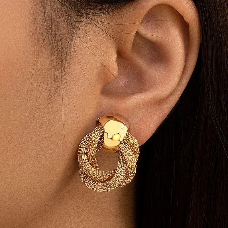 Boucle D'oreille Luxe Maille Torsadée Vintage, portée par une mannequin, on ne voit que son oreille avec la boucle. Image