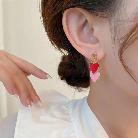 Boucle D'oreille Originale Femme Pendante Cœurs, portée par une mannequin, on voit son oreille, son cou et ses cheveux attachés en chignon bas.