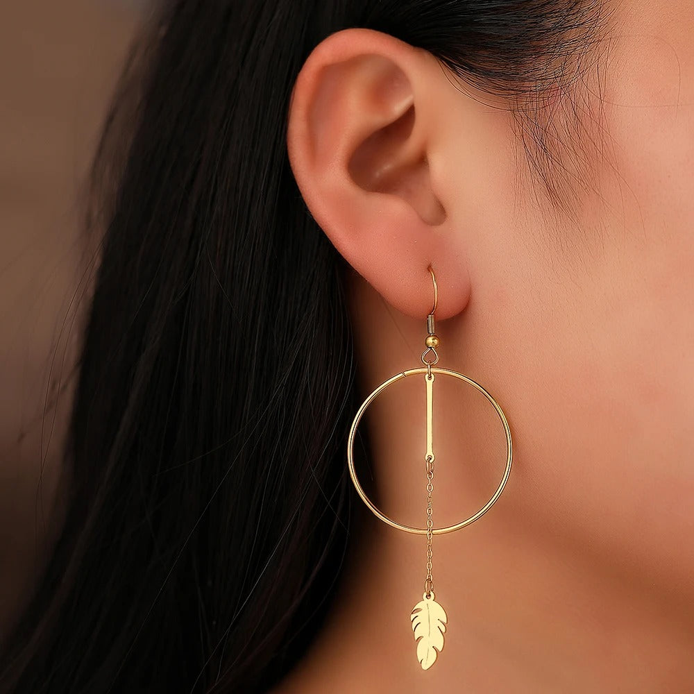 Boucle D'oreille Pendante Cercle Plume en Acier Inoxydable, portée ar une mannequin de profil.