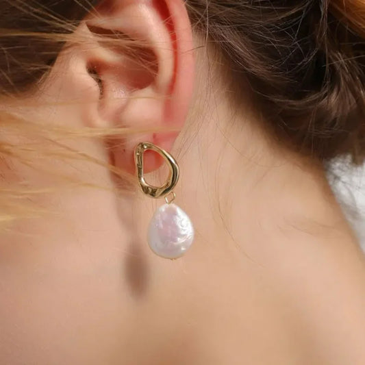 Boucle D'oreille Pendante avec Perle Plate, portée par une mannequin de profil, on ne voit pas son visage.