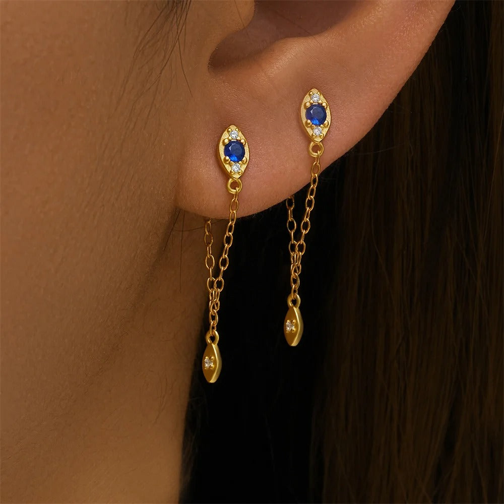 Boucle D'oreille Pendante Style Œil De Protection en paire porté par une femme, on ne voit que la bas de son oreille et ses cheveux. Image